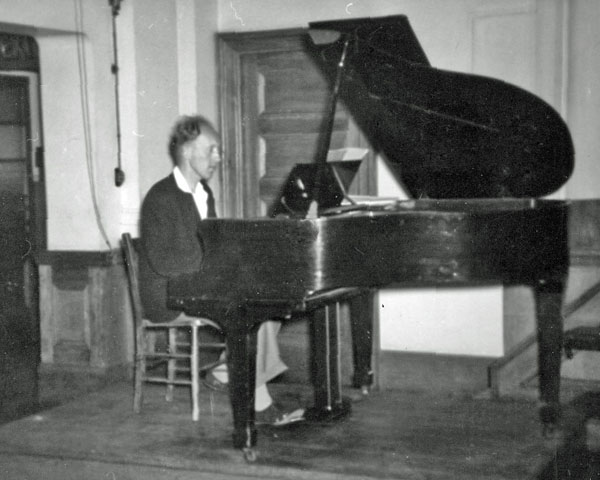 Peter Cork, seated at the piano in the hall of Dagenham County High school